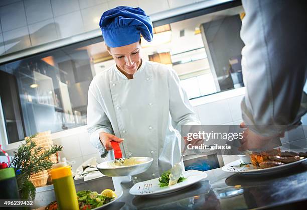 female chef places finishing touches on meal. - one person cooking stock pictures, royalty-free photos & images