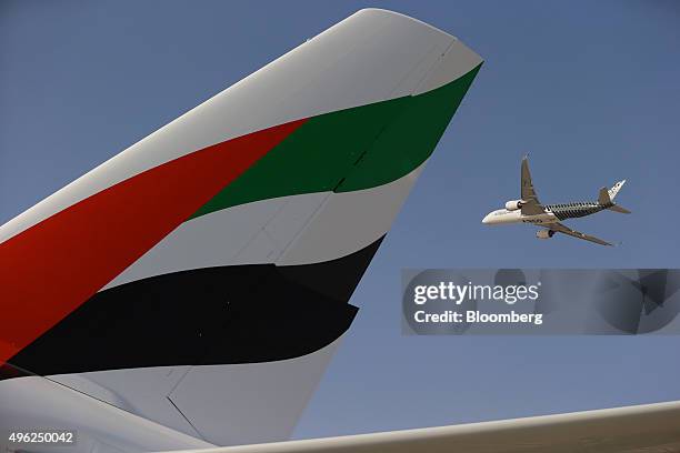 An Airbus A350 XWB flies past the tail fin of an Airbus A380-800, operated by Emirates Airline, during an aerial display on the opening day of the...