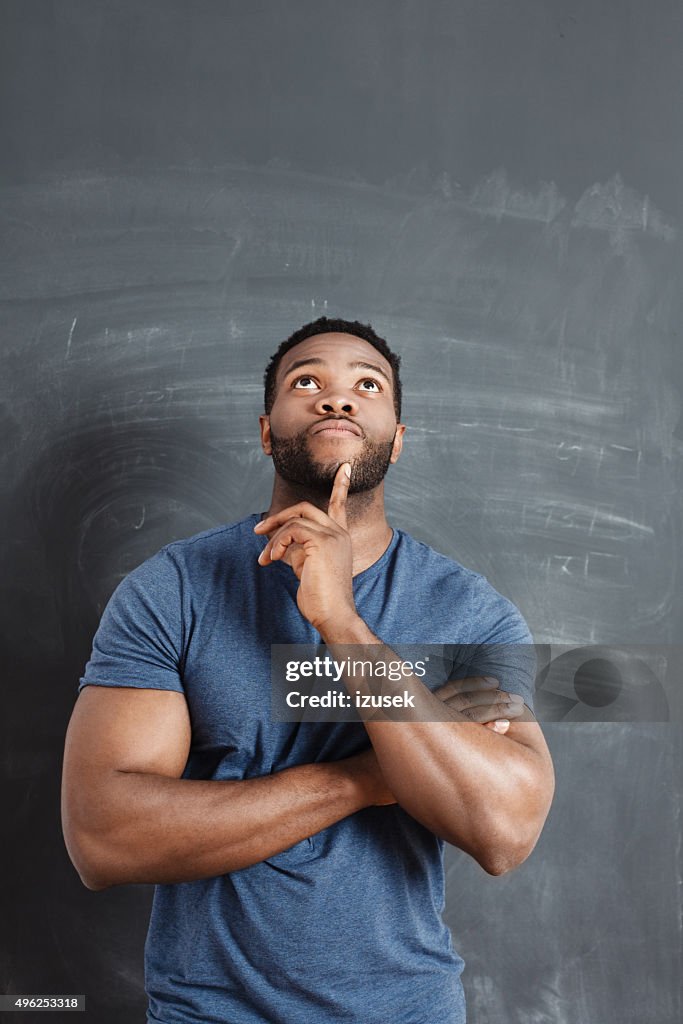 Pensive afro american man against blackboard