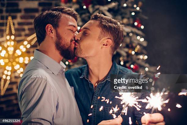 couple celebrating christmas together. - gay kiss stock pictures, royalty-free photos & images