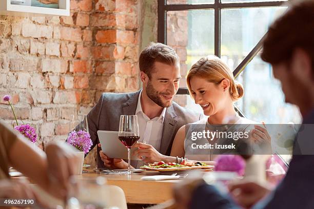 elegant couple using a digital tablet in the restaurant - dinner program stock pictures, royalty-free photos & images