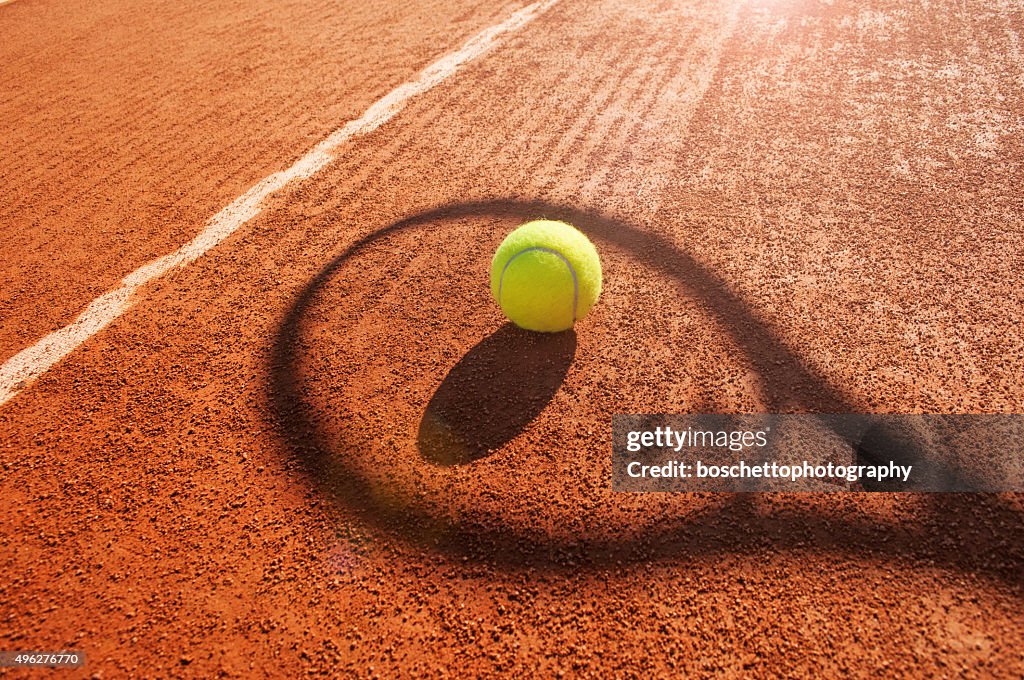Tennis-ball und Schläger Schatten auf Sandplatz