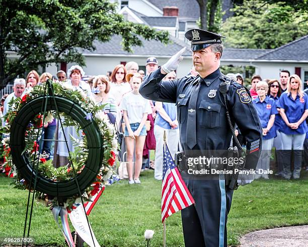 Police officer salutes as part of Memorial Day ceremony honoring those who fought.