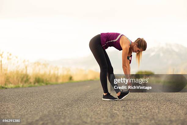 female runner stretches along road in utah - stretch hamstrings stock pictures, royalty-free photos & images