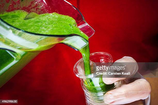 The staff at a stand of sKeimling Naturkost GmbH pours a sample of a green smoothie into a plastic cup at the Veggie World 2015 Vegan Trade Fair on...