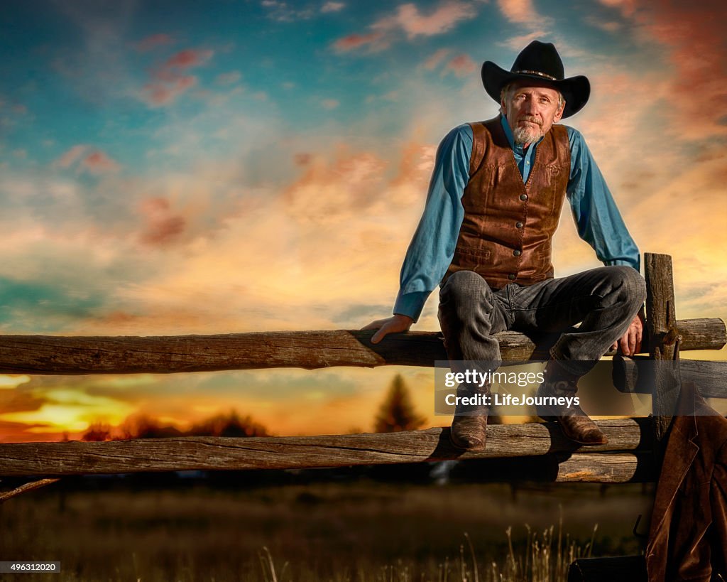 Iconic Cowboy Sitting On A Rail Fence In The Sunset