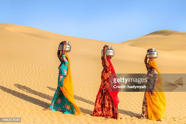 indische frauen tragen von wasser auf den kopf von lokalen gut - woman in red sari stock-fotos und bilder