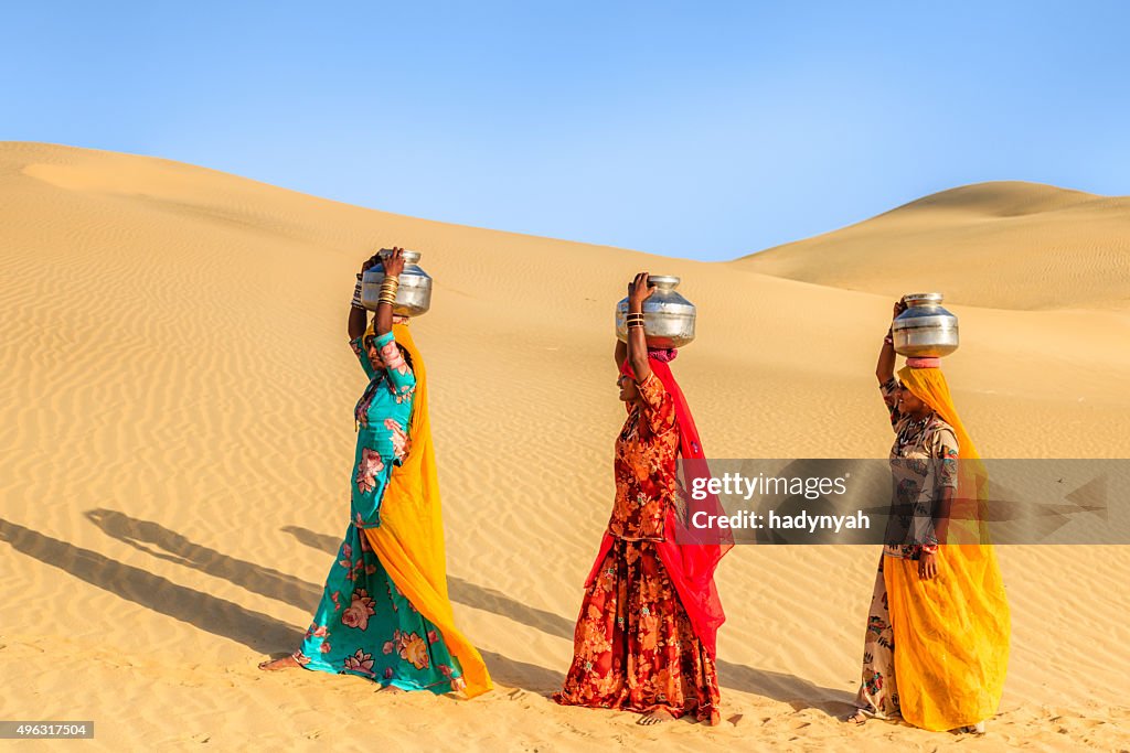 Indian women carrying on their heads water from local well
