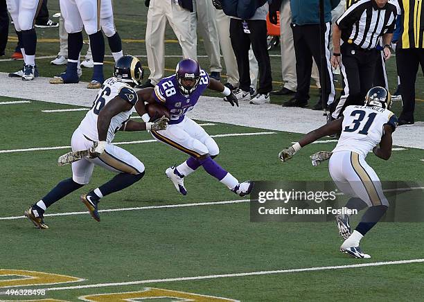 Adrian Peterson of the Minnesota Vikings carries the ball against Akeem Ayers and Maurice Alexander of the St. Louis Rams during the fourth quarter...