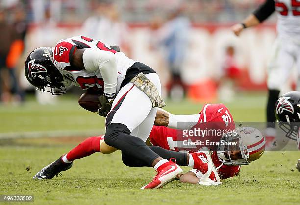 Jerome Simpson of the San Francisco 49ers catches the ball and then is hit by Ricardo Allen of the Atlanta Falcons and then Phillip Adams of the...