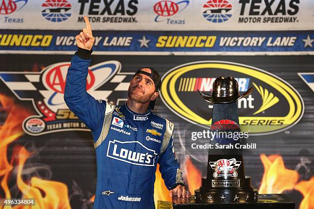 Jimmie Johnson, driver of the Lowe's Chevrolet, celebrates with the trophy in Victory Lane after winning the NASCAR Sprint Cup Series AAA Texas 500...