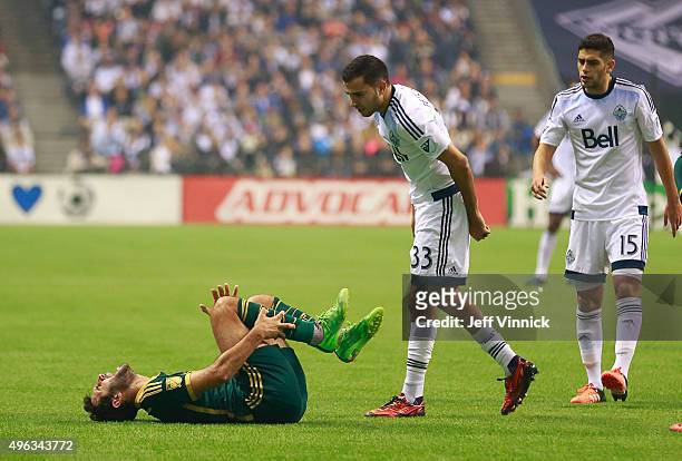 Steven Beitashour and Matias Laba of the Vancouver Whitecaps FC look on as Diego Valeri of the Portland Timbers writhes in pain on the turf during...