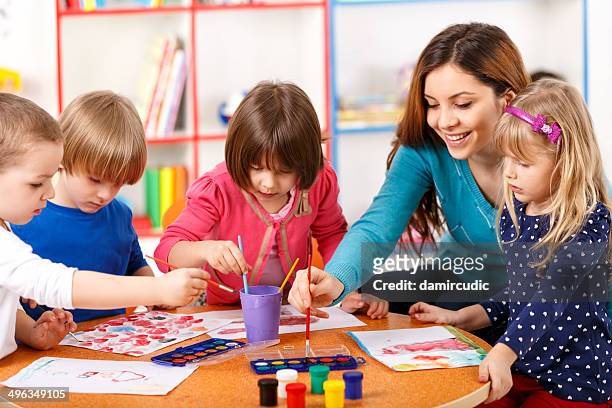 group of elementary age children in art class with teacher - craft table stock pictures, royalty-free photos & images
