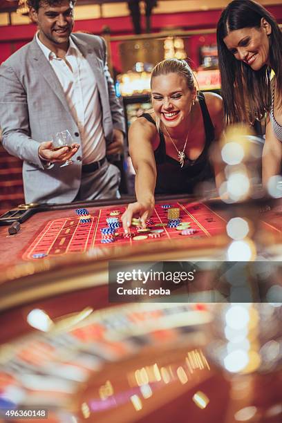 excited friends   gambling at roulette in casino - roulotte stock pictures, royalty-free photos & images