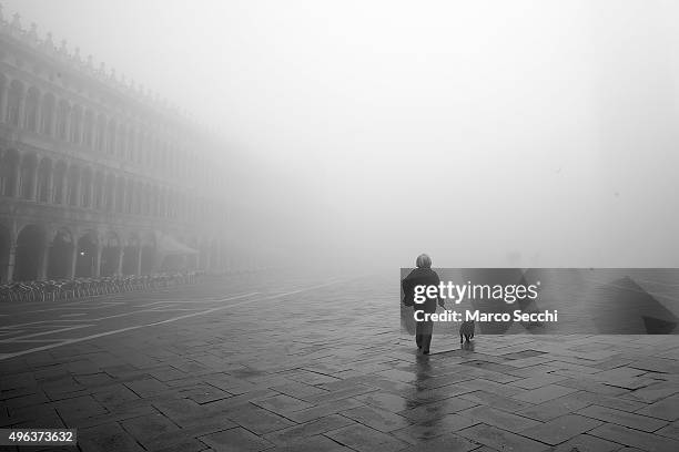 Woman walks her dog under thick fog in Saint Mark's Square on November 9, 2015 in Venice, Italy. Venice and the lagoon woke up this morning under a...