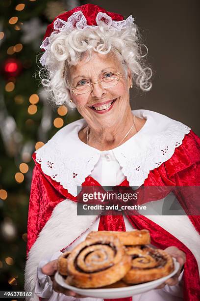 ms. claus with plate of cinnamon rolls - mrs claus stock pictures, royalty-free photos & images