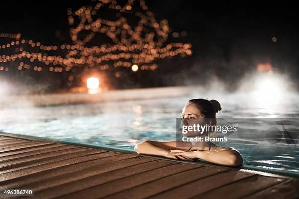 young woman relaxing in heated swimming pool during winter night. - relaxing spa stock pictures, royalty-free photos & images