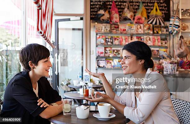 girlfriends talking over a coffee at café - 2 frauen gespräch ohne männer cafe stock-fotos und bilder