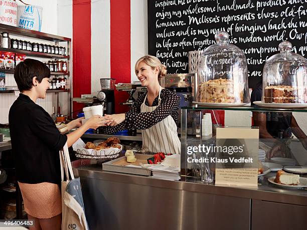 woman handing to-go coffee to customer at café - women serving coffee stock-fotos und bilder