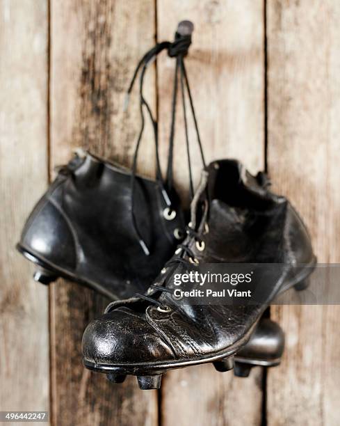 old leather football boots hanging on hook - studded stock-fotos und bilder