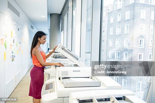 attractive young businesswoman using photocopier in modern office - by the photocopier stock pictures, royalty-free photos & images