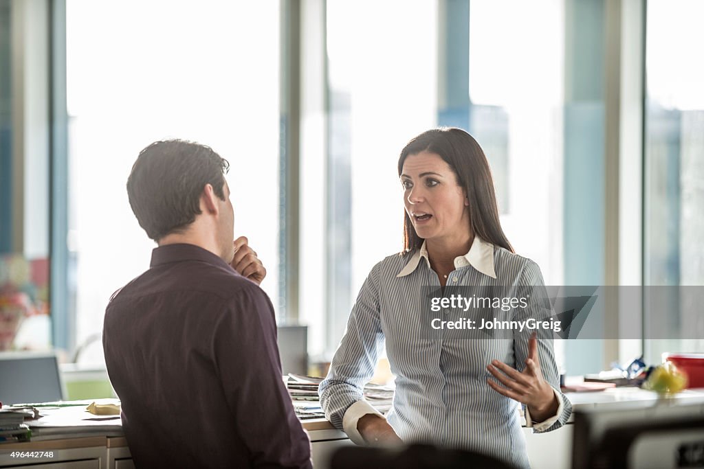 Two business people having serious discussion in modern office