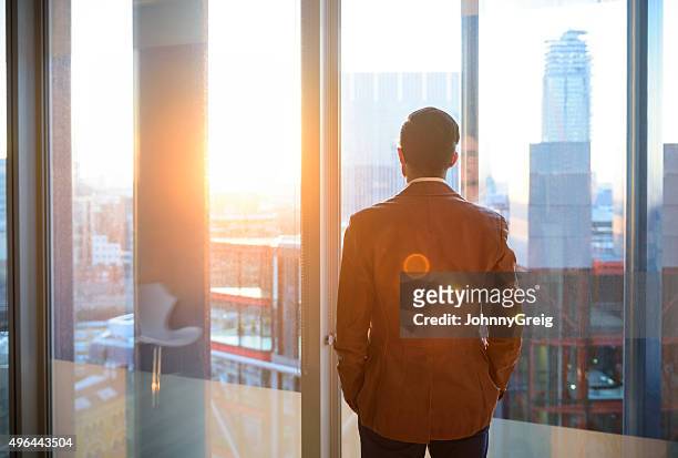 businessman looking through office window in sunlight - new start stock pictures, royalty-free photos & images