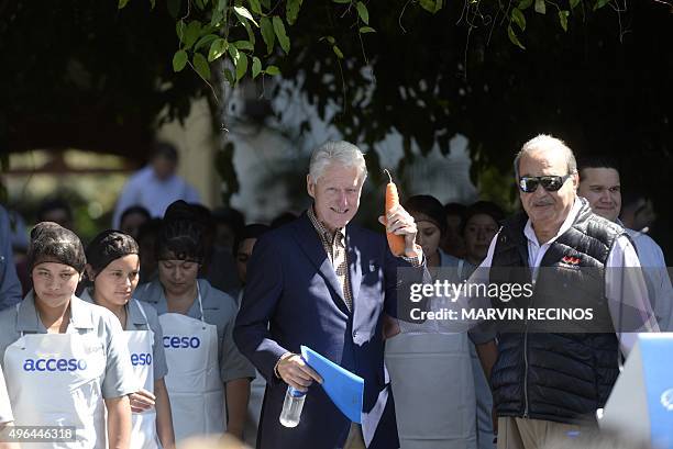 Former US President Bill Clinton shows a carrot next to Mexican Tycoon Carlos Slim in Santa Tecla, El Salvador on November 9 during a visit to verify...