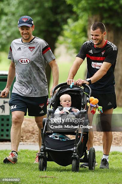 Brent Stanton, with his son Aiden in the pram, walks with assistant coach Mark Harvey during an Essendon Bombers AFL pre-season training session at...