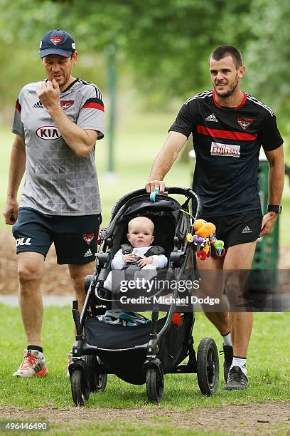 Brent Stanton, with his son Aiden in the pram, walks with assistant coach Mark Harvey during an Essendon Bombers AFL pre-season training session at...