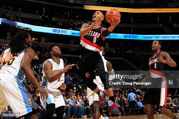 Damian Lillard of the Portland Trail Blazers drives to the basket against Emmanuel Mudiay and Kenneth Faried of the Denver Nuggets at Pepsi Center on...