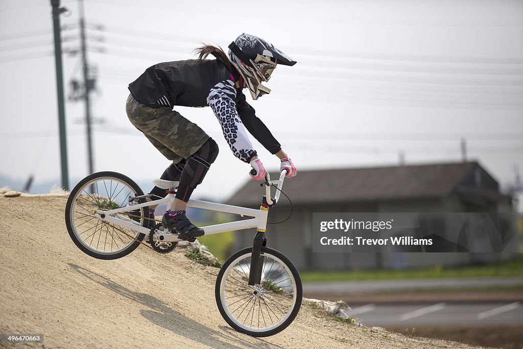 A young woman racing a BMX bike on a track