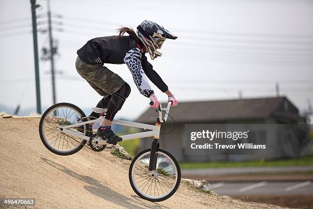 a young woman racing a bmx bike on a track - crossfietsen stockfoto's en -beelden