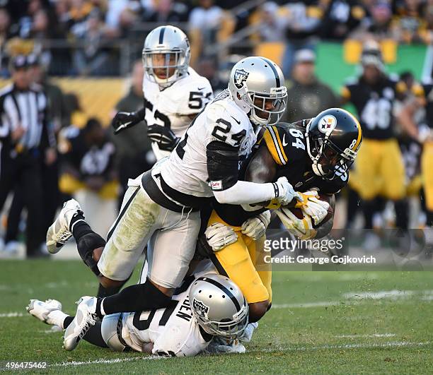 Safety Charles Woodson and cornerback DJ Hayden of the Oakland Raiders tackle wide receiver Antonio Brown of the Pittsburgh Steelers during a game at...