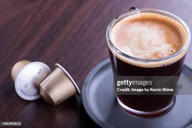 coffee cup and two pods on table - coffee capsules stock pictures, royalty-free photos & images