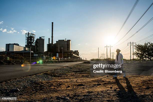 Worker walks past the Marikana platinum mine, operated by Lonmin Plc, in Marikana, South Africa, on Monday, Nov. 9, 2015. Lonmin's warning that it...