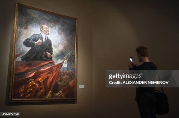 Visitor takes pictures of Soviet artist Aleksandr Gerasimov's painting "Lenin on the Tribune" displayed in the exhibition "Romantic Realism. Soviet...