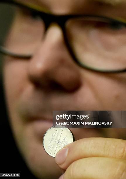 An official of Belarus' National Bank shows the new Belarus' ruble coin during a presentation in Minsk on November 10, 2015. Belarus will slash four...