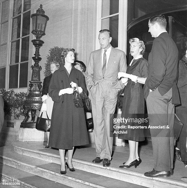 The American actor Gary Cooper with the American actress and wife Veronica Balfe and the daughter Maria Cooper waiting at the entrance of a building....