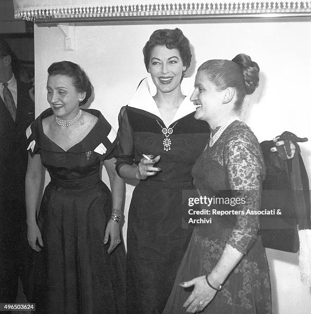 The American actress Ava Gardner chatting with the Italian stylists Micol and Giovanna Fontana at a party in their atelier. Rome, 1957