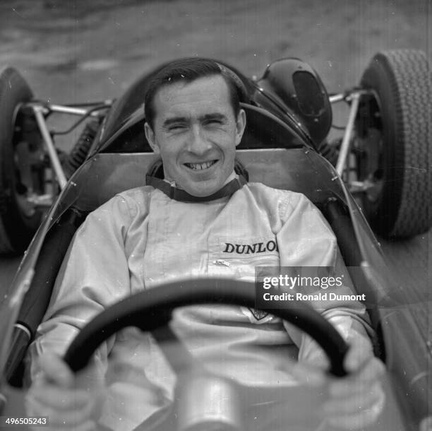 British racing driver Jackie Stewart, sitting in his car wearing his driving overalls, October 5th 1964.