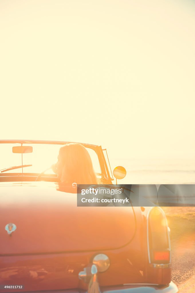 Femme conduire une voiture décapotable à la plage.