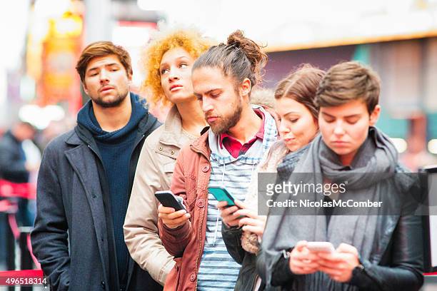 five young adults waiting in line some using phones - 排隊等侯 個照片及圖片檔