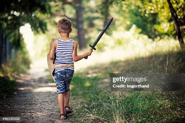 litte junge spielt knight zu fuß auf waldweg - sword stock-fotos und bilder