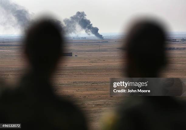 Kurdish forces overlook a burning oil well on November 10, 2015 near the ISIL-held town of Hole, Rojava, Syria. Troops from the Syrian Democratic...