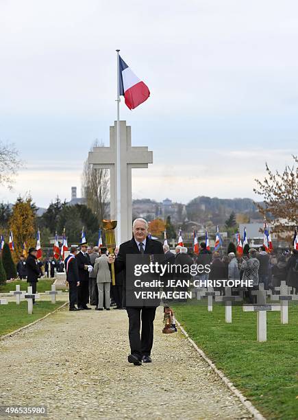 Man carries an eternal flame and torch during a dedication ceremony for seven unknown French WWI soldiers on November 10, 2015 in Verdun, eastern...