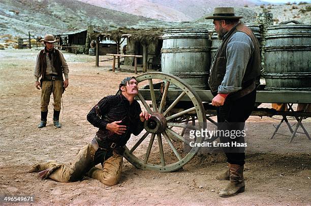 American actor Chuck Connors as Buck Hannassey, dying at the hands of his father Rufus Hannassey, played by Burl Ives , in a scene from the western...