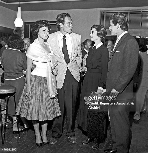 American actor Charlton Heston hugging his wife and American actress Lydia Clarke while talking to British actress Audrey Hepburn and British actor...