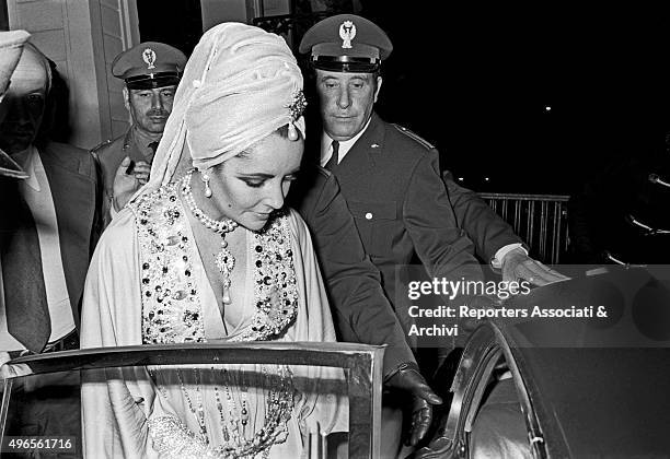 British-born American actress Elizabeth Taylor getting into the car surrounded by the policemen after the 'Rodolfo Valentino' award ceremony at...