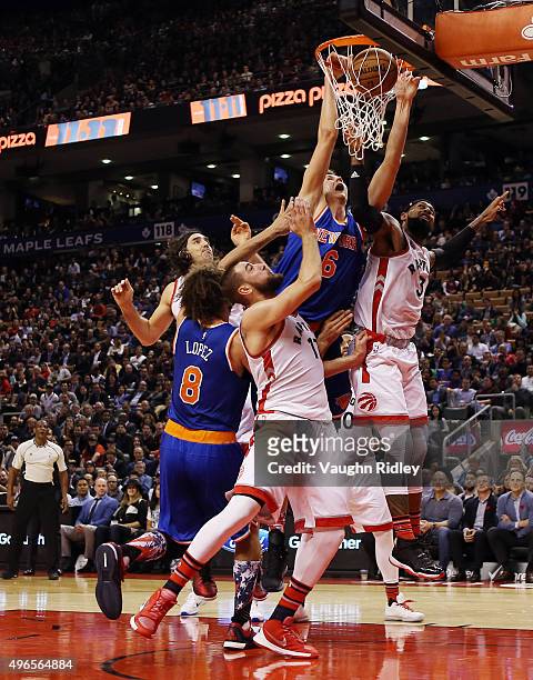 Kristaps Porzingis of the New York Knicks scores as Jonas Valanciunas and James Johnson of the Toronto Raptors defend during an NBA game at the Air...